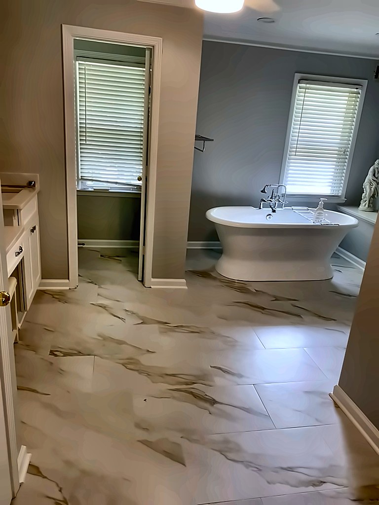 Primary bathroom with pedestal tub and marble-look tile